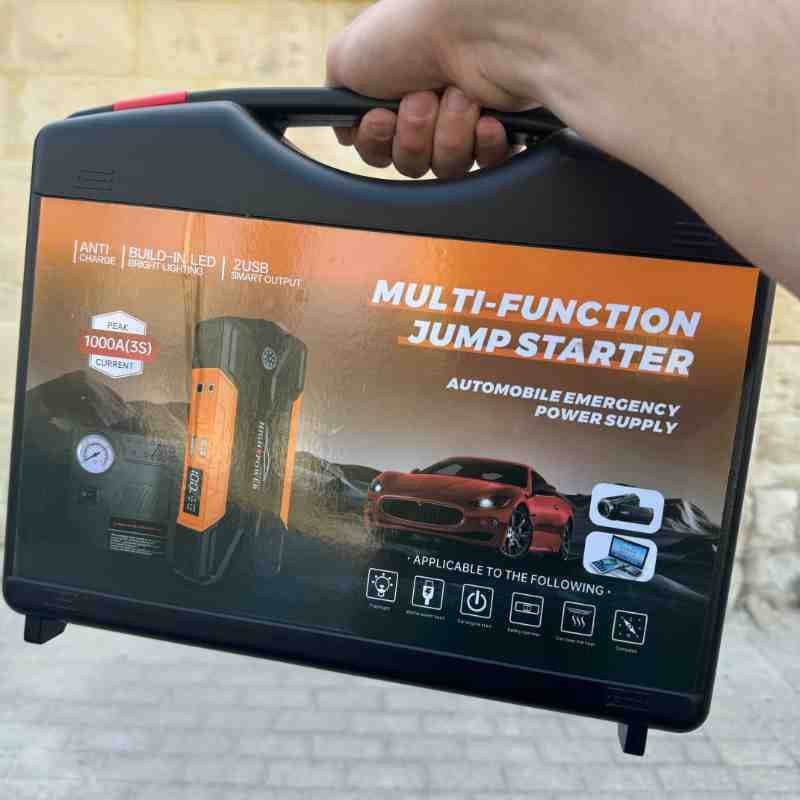 Person holding a multi-function jump starter case—helpful tool when learning how many amps to jump start car in emergencies.