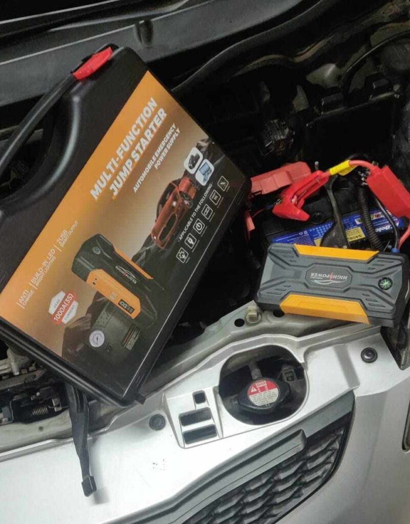 Portable jump starter connected under car hood—great visual for understanding how many amps to jump start car safely and effectively.
