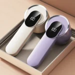 Beige and purple lint removers with digital displays lying side by side in a tray