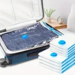 Flat compressed vacuum bag packed inside a suitcase for travel, with folded bags stacked beside it